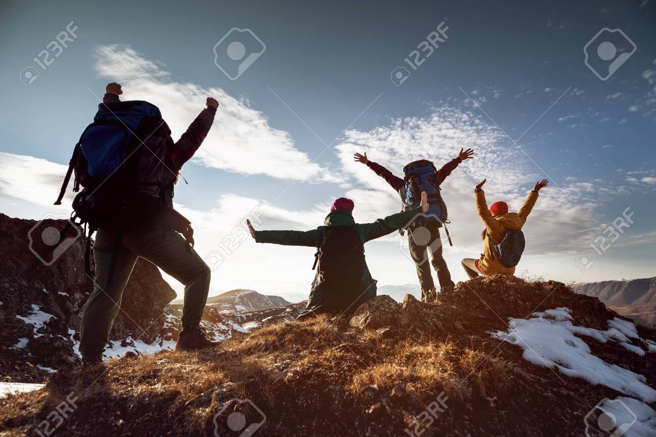 Four happy hikers stands in winner poses at mountain top at sunset time - 157019911 Four happy hikers stands in winner poses at mountain top at sunset time - 157019911