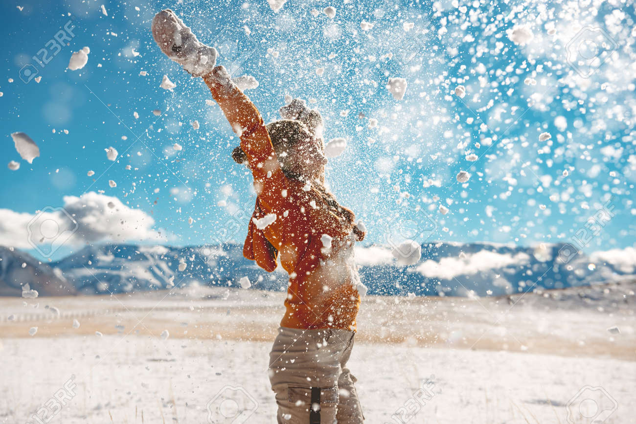 Adult girl throws snow and having fun against mountains. First snow concept - 157587523 Adult girl throws snow and having fun against mountains. First snow concept - 157587523