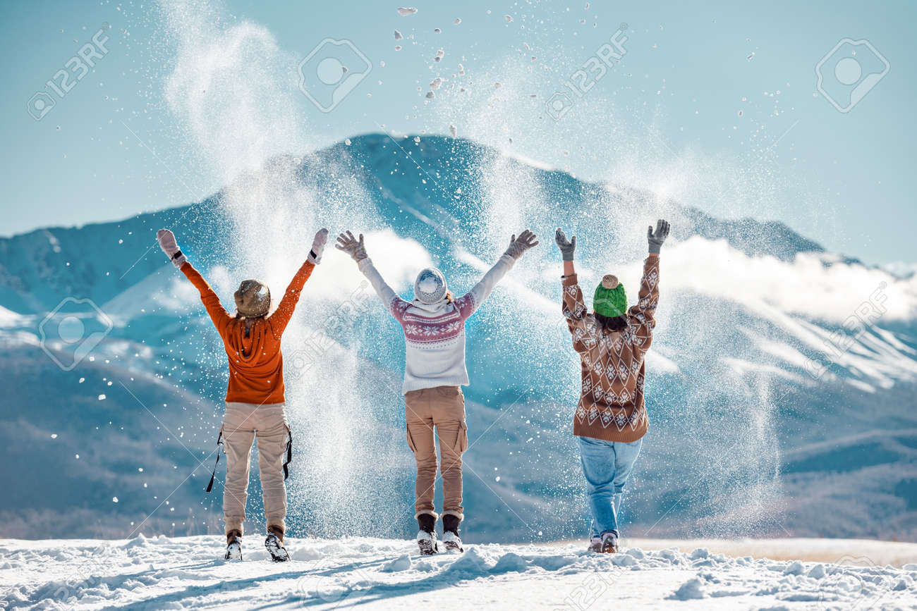 Three happy adult girls are having fun and throws first snow on background of mountains. Travel in winter time concept - 157799288 Three happy adult girls are having fun and throws first snow on background of mountains. Travel in winter time concept - 157799288