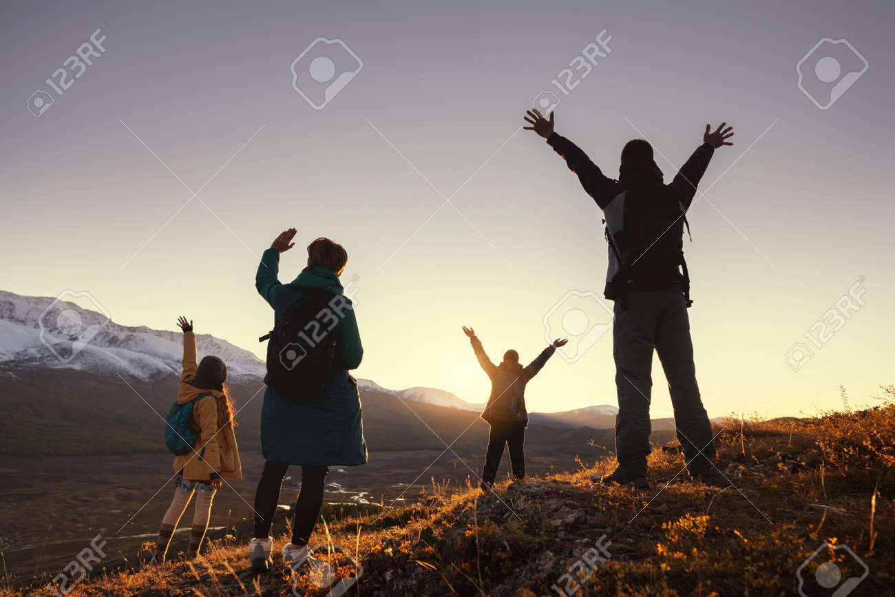 Four young hikers greetings with raised arms sunset in mountains - 158135057 Four young hikers greetings with raised arms sunset in mountains - 158135057