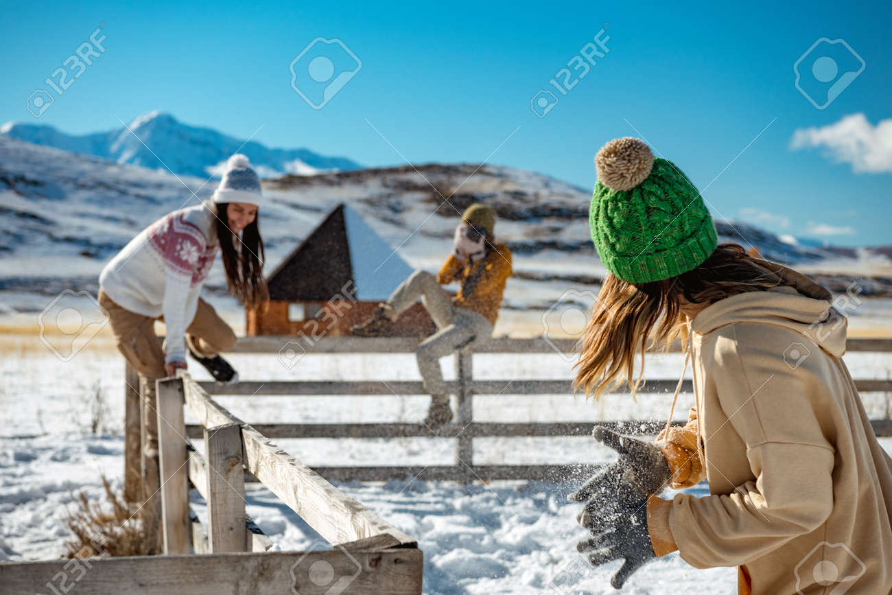 Three happy young girlfriends are having fun at wooden fence at wintertime outdoors in mountains. Winter vacations concept - 159094872 Three happy young girlfriends are having fun at wooden fence at wintertime outdoors in mountains. Winter vacations concept - 159094872