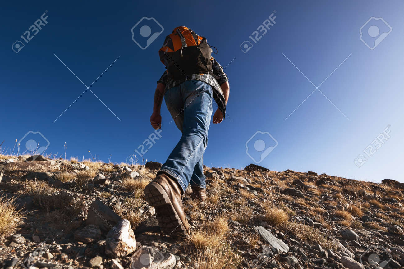 Unrecognizable male traveler or hiker goes uphill. Closeup photo from boots - 159685120 Unrecognizable male traveler or hiker goes uphill. Closeup photo from boots - 159685120