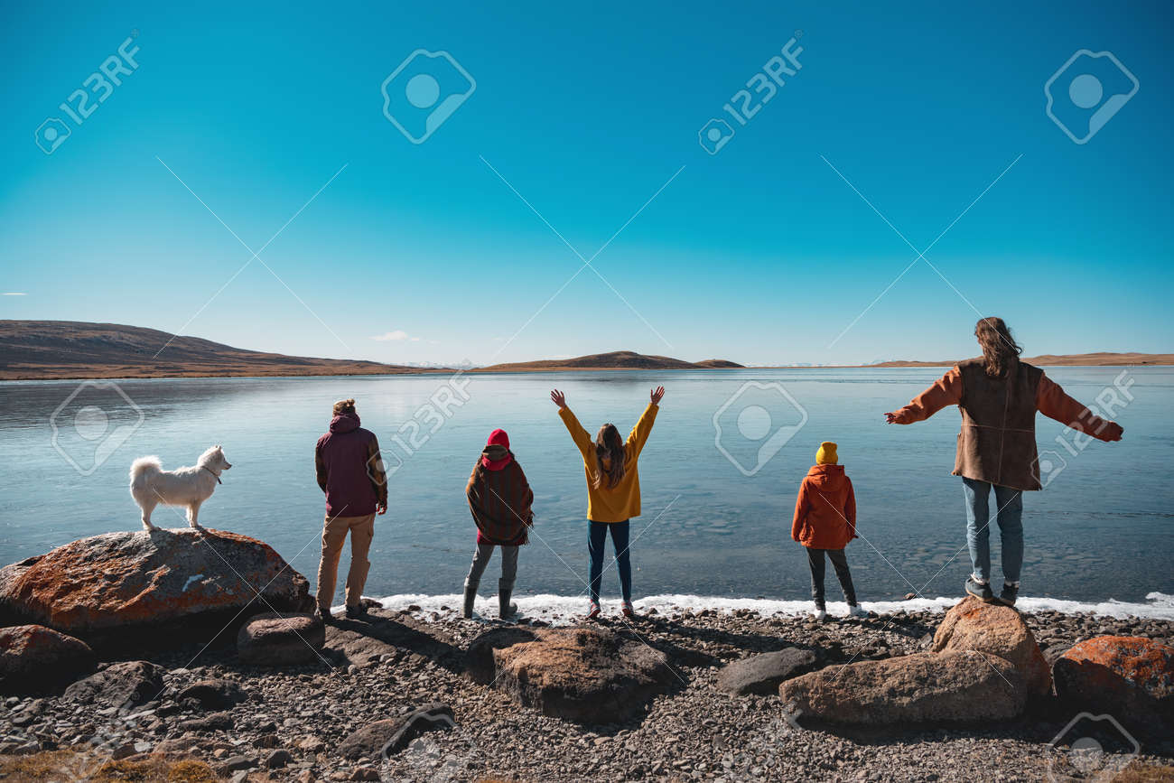 Group of five young friends with white husky dog are having rest and looking at mountain lake. Altai mountains, Siberia, Russia - 159900772 Group of five young friends with white husky dog are having rest and looking at mountain lake. Altai mountains, Siberia, Russia - 159900772