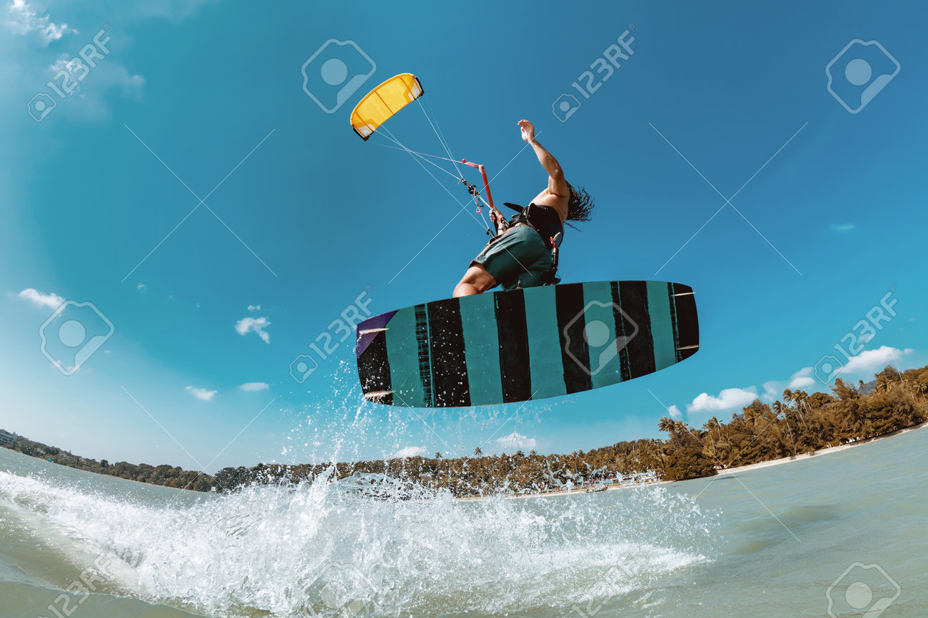 Athlete wakeboarder jumps with kite at sea bay. Phuket island, Thailand - 162389384 Athlete wakeboarder jumps with kite at sea bay. Phuket island, Thailand - 162389384