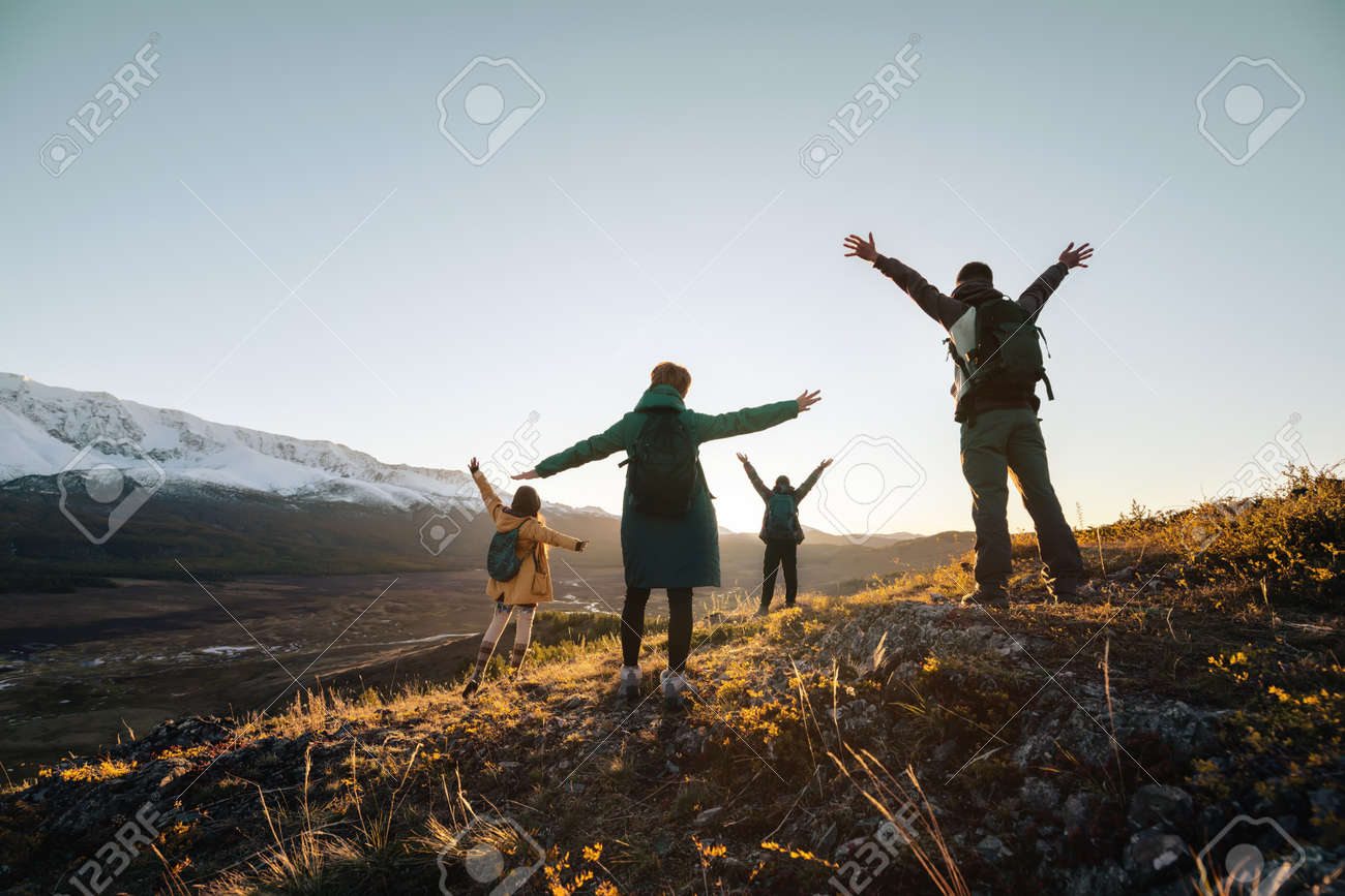 Happy hikers stands with raised arms and looking at sunset mountains - 163777778 Happy hikers stands with raised arms and looking at sunset mountains - 163777778