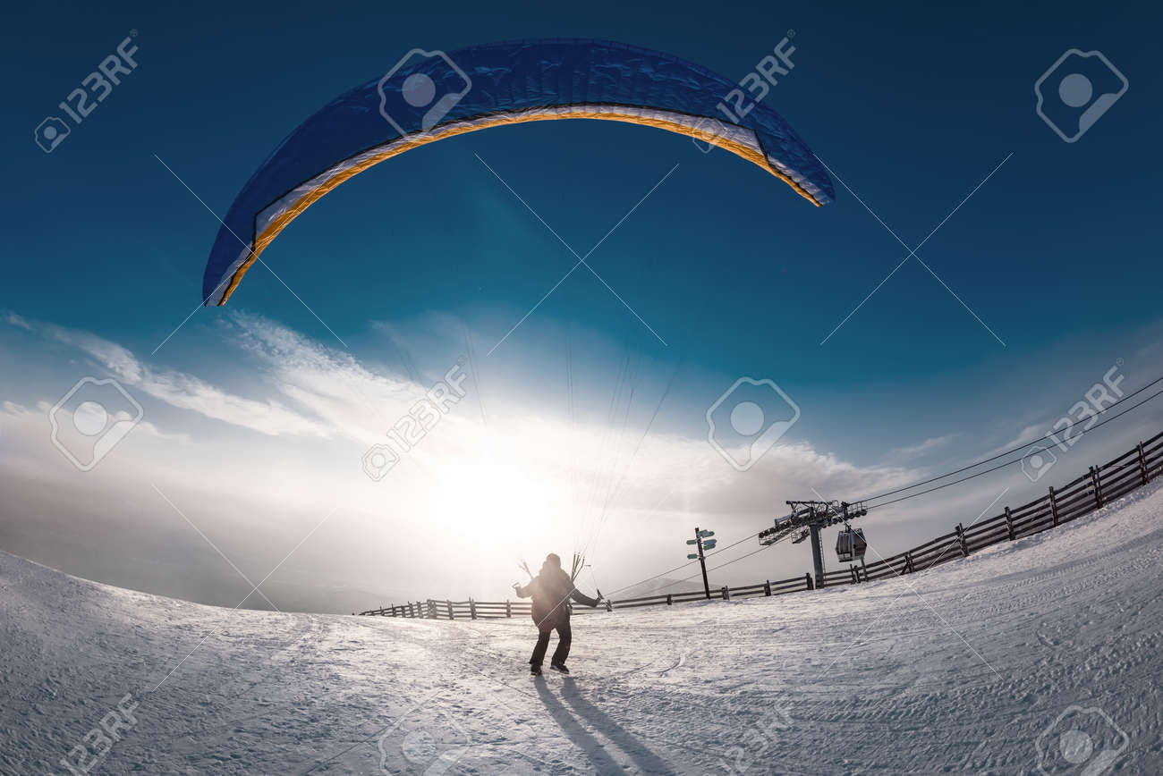 Lonely skydiver is taking off from mountain top at ski resort in sunset time. Sheregesh resort, Siberia, Russia - 165063005 Lonely skydiver is taking off from mountain top at ski resort in sunset time. Sheregesh resort, Siberia, Russia - 165063005