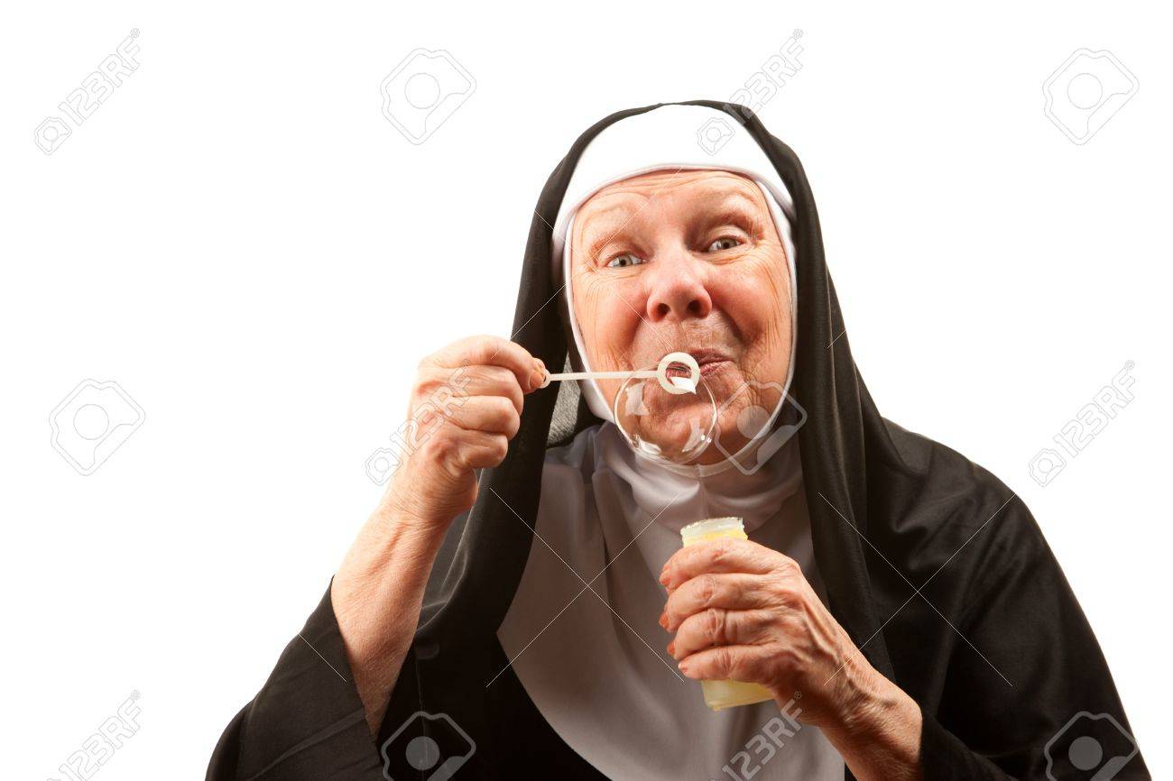 funney nun in religious habit and veil blowing bubbles stock photo