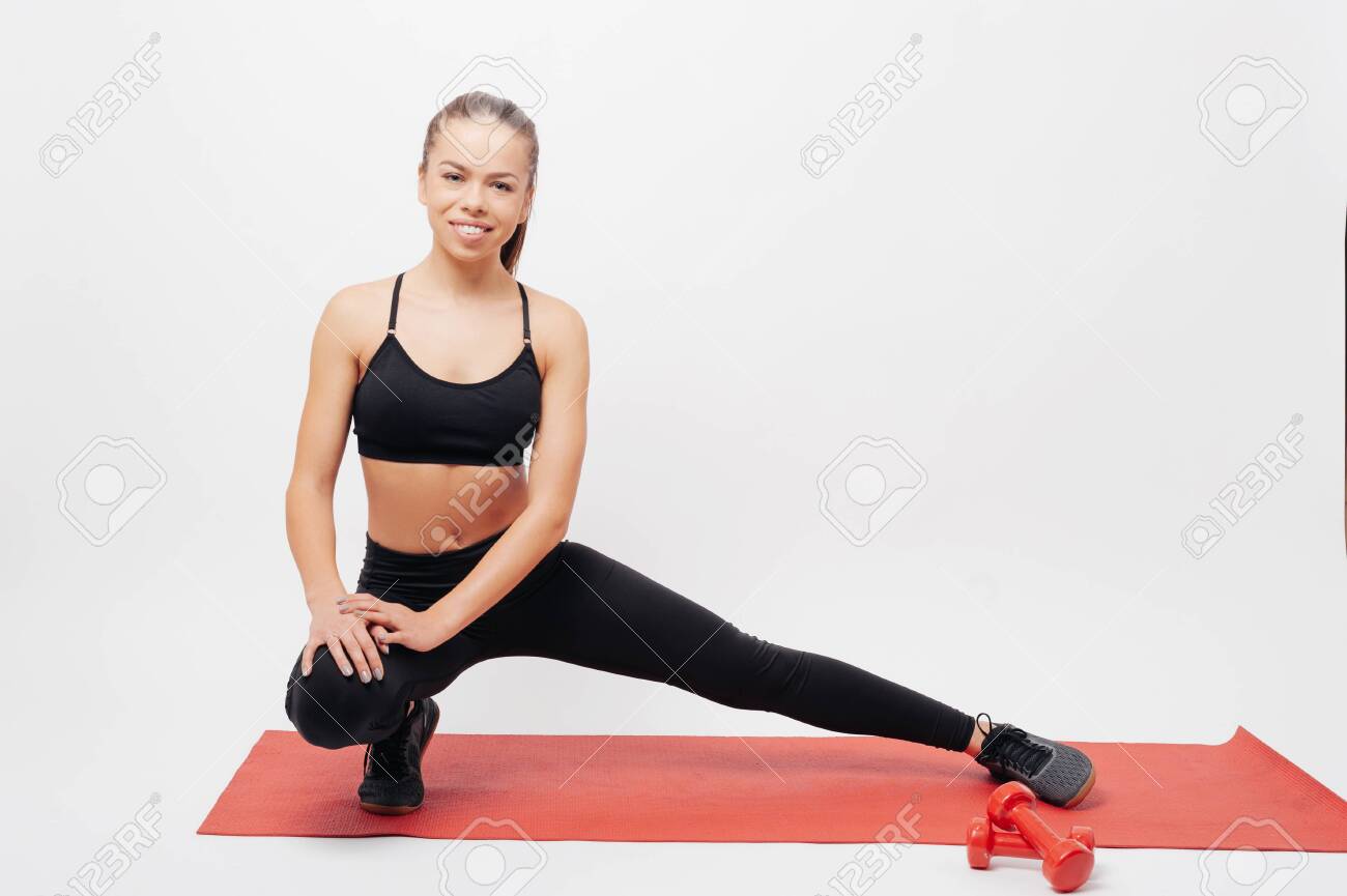 Happy sportswoman lunging and looking at camera - 132374946 Happy sportswoman lunging and looking at camera - 132374946