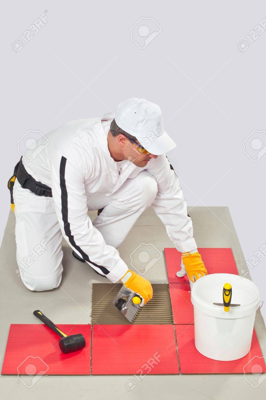 Worker Applies Tile Adhesive With Notched Trowel Tile On A Floor