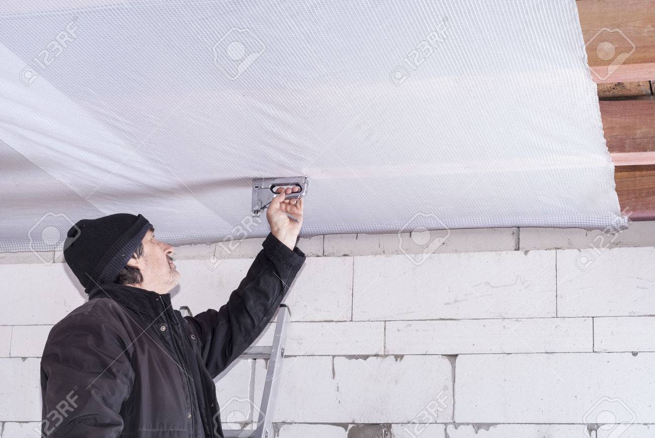 Builder Attaches Vapor Barrier To Wooden Beams On The Ceiling