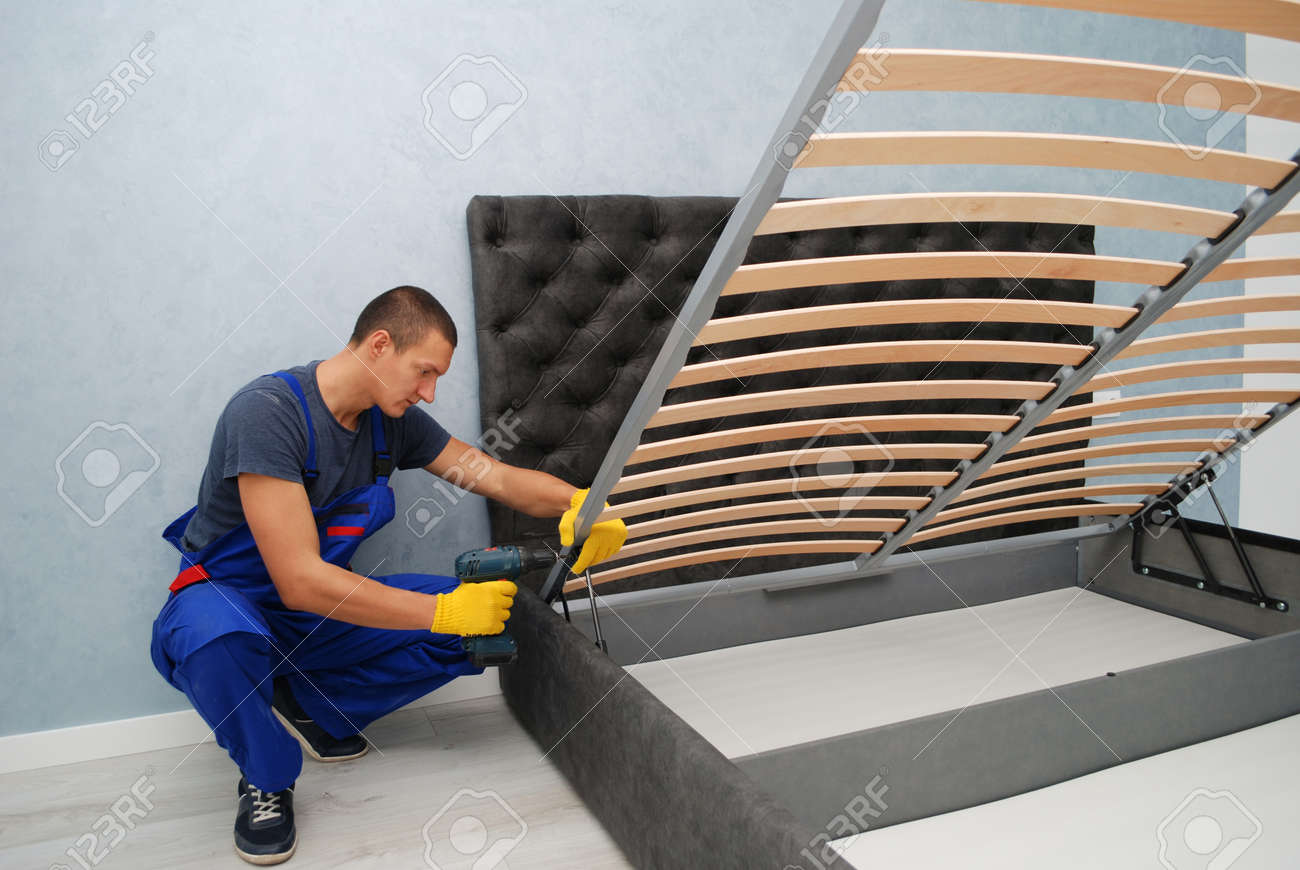 the master is assembling a new bed with a lifting mechanism in the buyer's apartment - 165451318 the master is assembling a new bed with a lifting mechanism in the buyer's apartment - 165451318