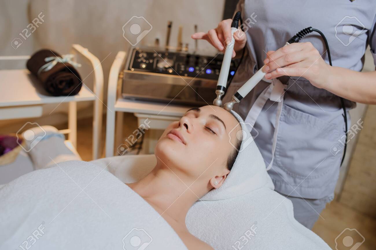 Lateral view of woman facial massage spa procedure. Electric stimulation facial skin care. Microcurrent lift face. Beauty spa procedure. Anti aging rejuvenation non surgical treatment in medical interior room - 151327770 Lateral view of woman facial massage spa procedure. Electric stimulation facial skin care. Microcurrent lift face. Beauty spa procedure. Anti aging rejuvenation non surgical treatment in medical interior room - 151327770