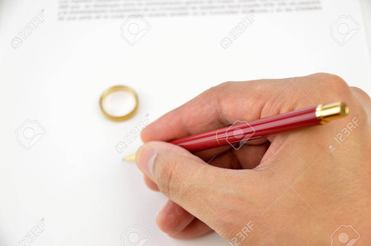 hand of a husband signing the divorce paper with wedding ring divorce contract