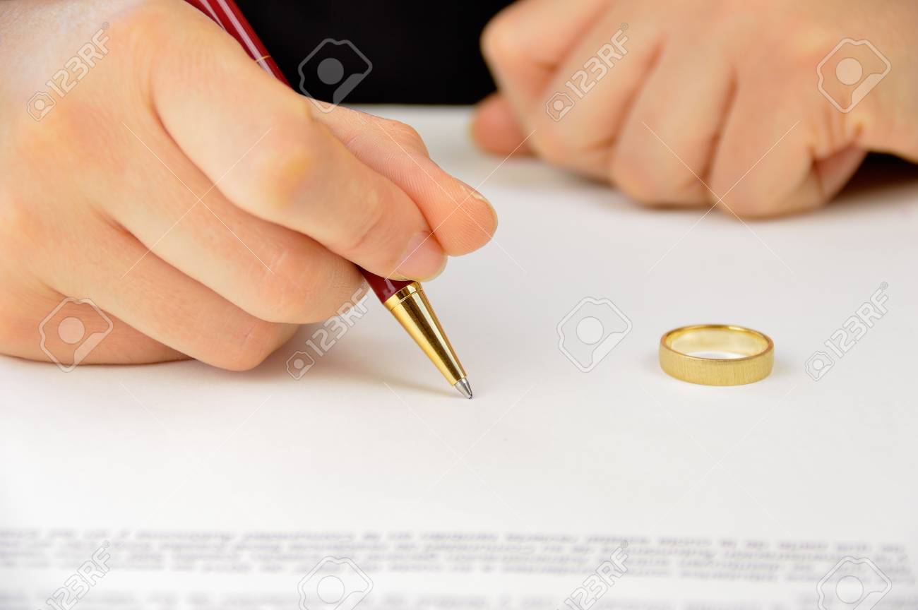 wife signing divorce agreement with the weeding ring on the contract divorce contract