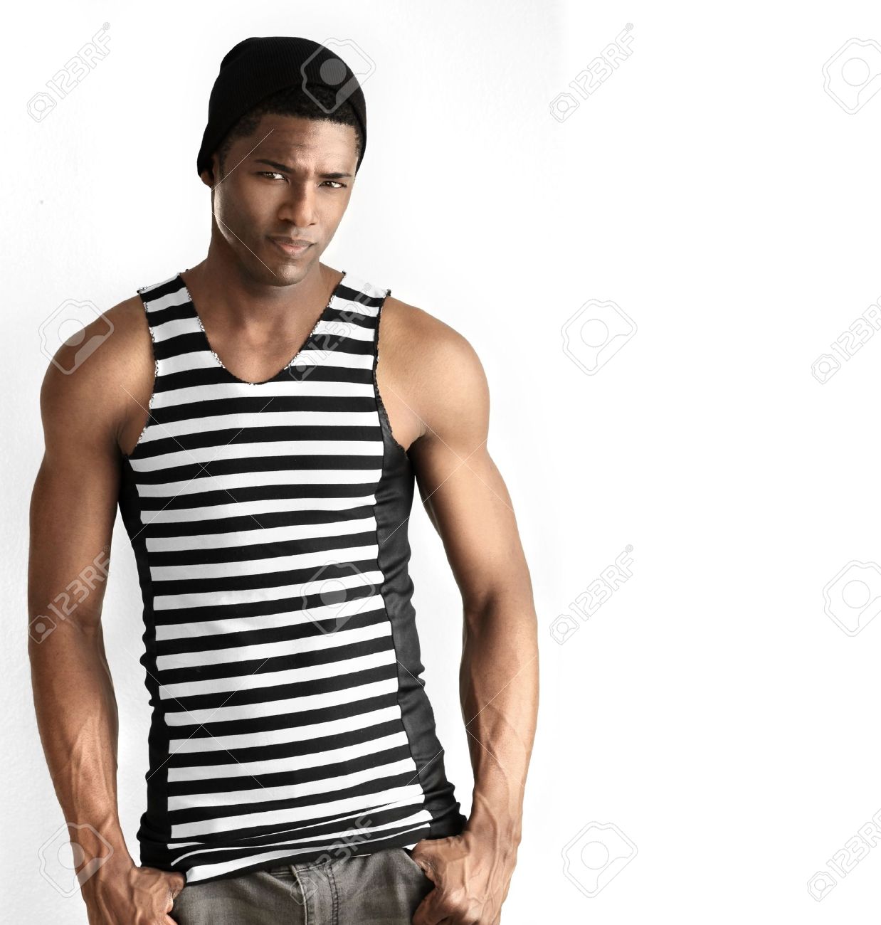 Fashion portrait of fit young male model in black and white striped trendy sleeveless shirt against