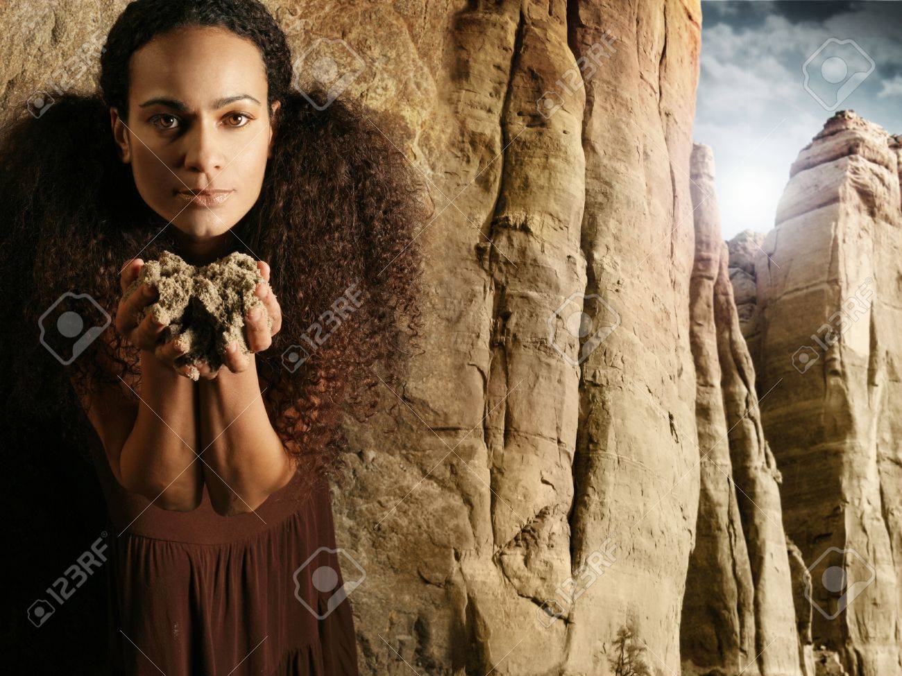 雄大な崖シーンのバック グラウンドに対して茶色のドレスに彼女の体に近い手で汚れを保持している女性のユニークな肖像画 の写真素材 画像素材 Image 13646211