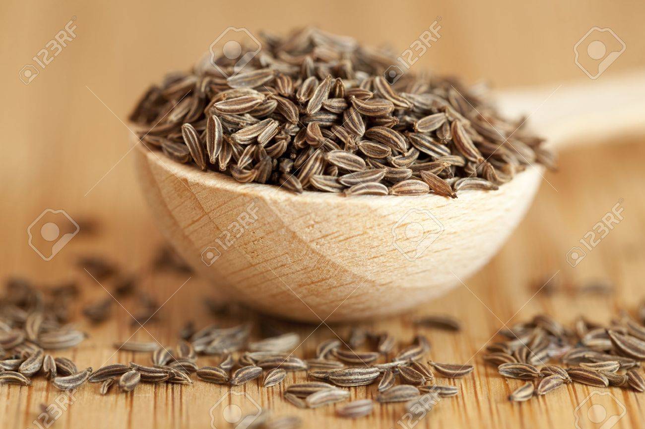 wooden spoon with cumin on brown board - 19500849 wooden spoon with cumin on brown board - 19500849