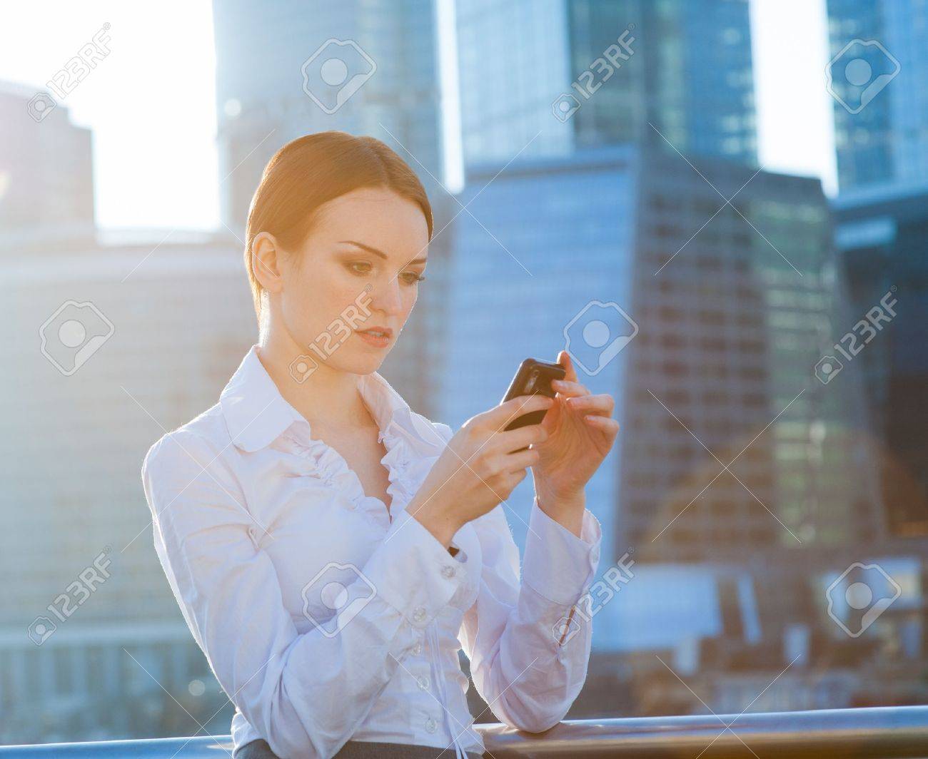 Business woman using smartphone. Sun beams, lens flare - 19203115 Business woman using smartphone. Sun beams, lens flare - 19203115
