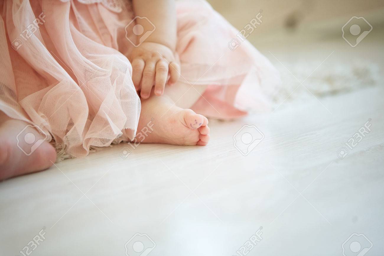 Photo Of Little Baby On The Floor With Drawn Smiley Face On Her