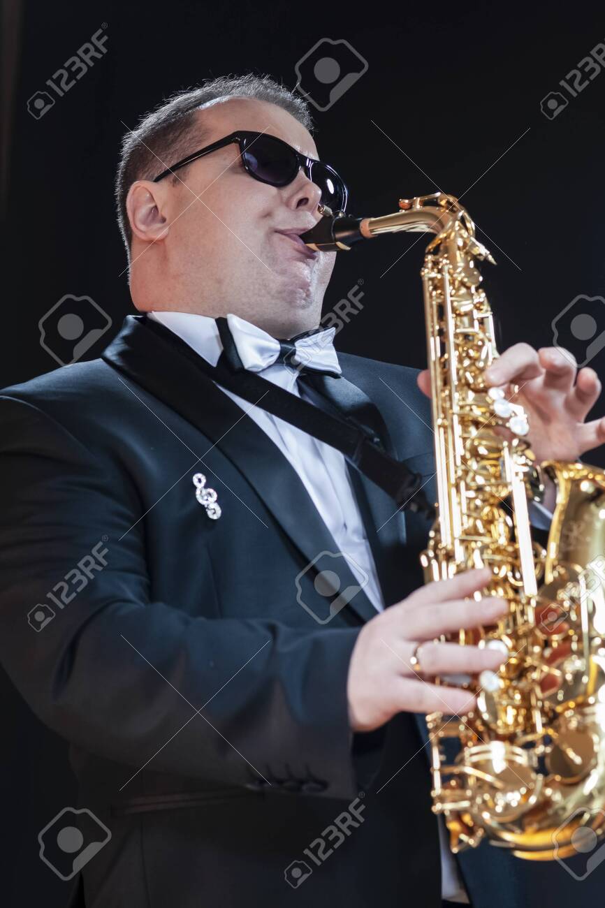 Portrait of Passionate and Extravagant Caucasian Saxophonist in Dark Suit Posing in Sunglasses Against Black. Vertical Image - 149772887 Portrait of Passionate and Extravagant Caucasian Saxophonist in Dark Suit Posing in Sunglasses Against Black. Vertical Image - 149772887