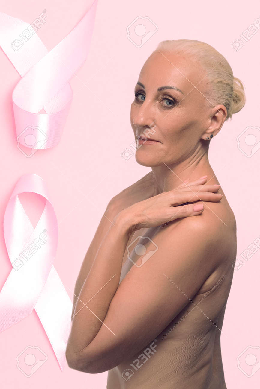 Caucasian Mature Topless Woman Over Pink Ribbon Background As Breast Cancer  Awareness Symbol And Women Healthcare Concept Of Campaign Against Cancer.  Horizontal Image Composition Stock Photo, Picture and Royalty Free Image.  Image