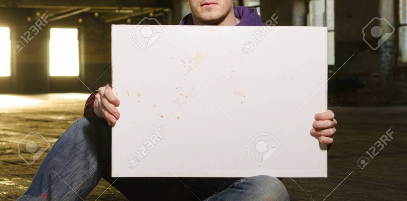 A white male holding an empty blank protest billboard in an urban warehouse setting. People power, power to the people. blank mock board for compositing. - 144428496 A white male holding an empty blank protest billboard in an urban warehouse setting. People power, power to the people. blank mock board for compositing. - 144428496