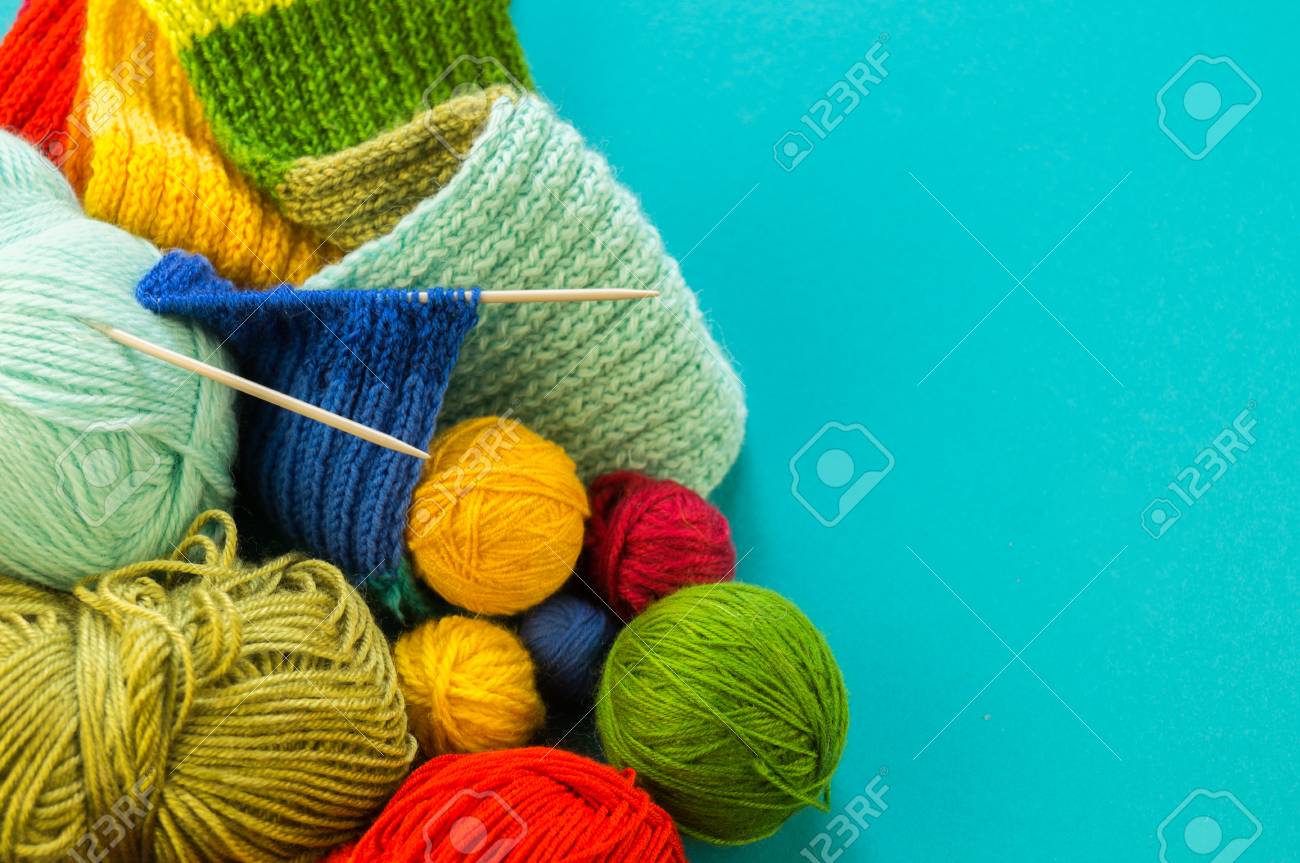 Knitting a rainbow scarf and hat. Basket with balls of wool, knitting needles. Blue background. Favorite work is a hobby. - 107647072 Knitting a rainbow scarf and hat. Basket with balls of wool, knitting needles. Blue background. Favorite work is a hobby. - 107647072