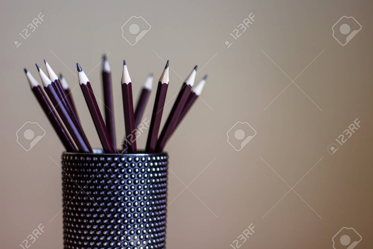 many graphite pencils standing in black glass container drawing