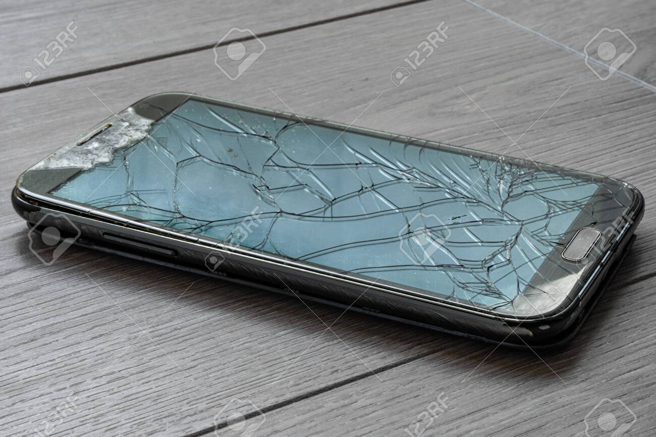 Broken smartphone on the floor. The screen is cracked and the phone is damaged. - 149445872 Broken smartphone on the floor. The screen is cracked and the phone is damaged. - 149445872