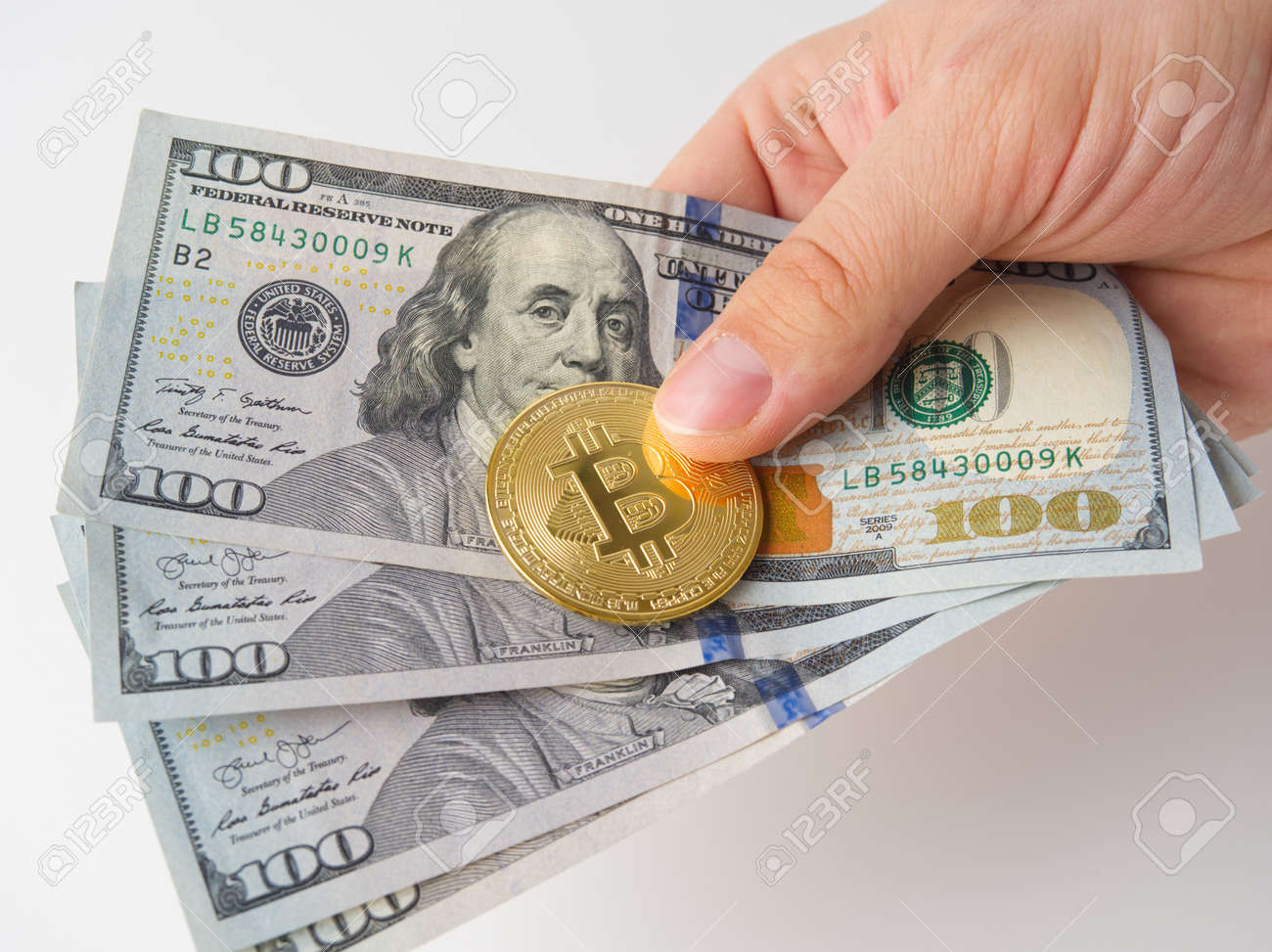 La Mano De Un Hombre Sostiene Billetes De 100 Dólares Y Un Bitcoin Dorado.  Fondo Blanco. El Concepto De Minería Y Minería De Criptomonedas. Fotos,  retratos, imágenes y fotografía de archivo libres