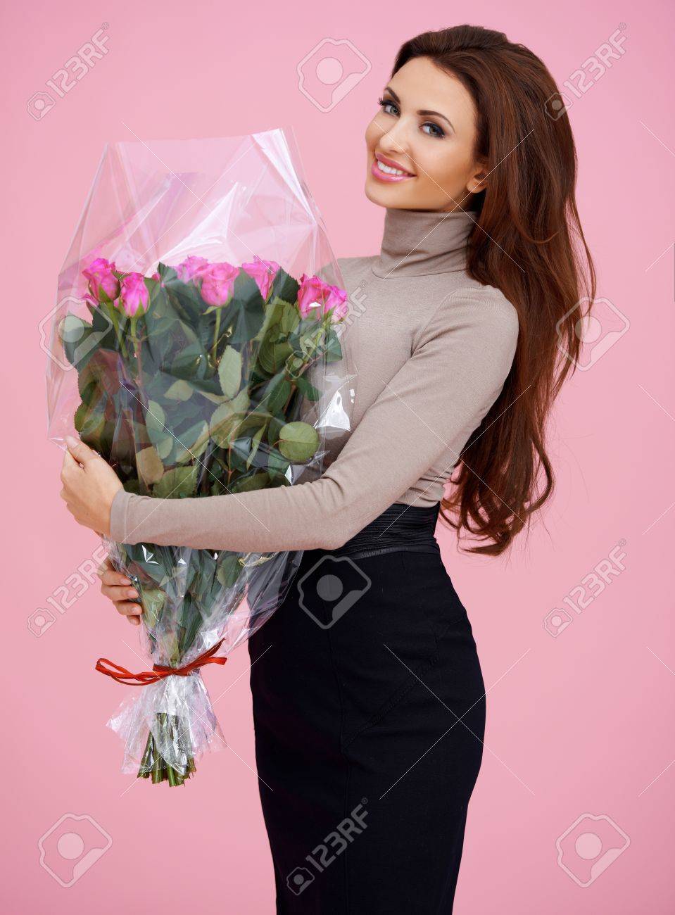 花の花束を保持を保持している幸せな長い茶色の髪若い女性のポーズ の写真素材 画像素材 Image
