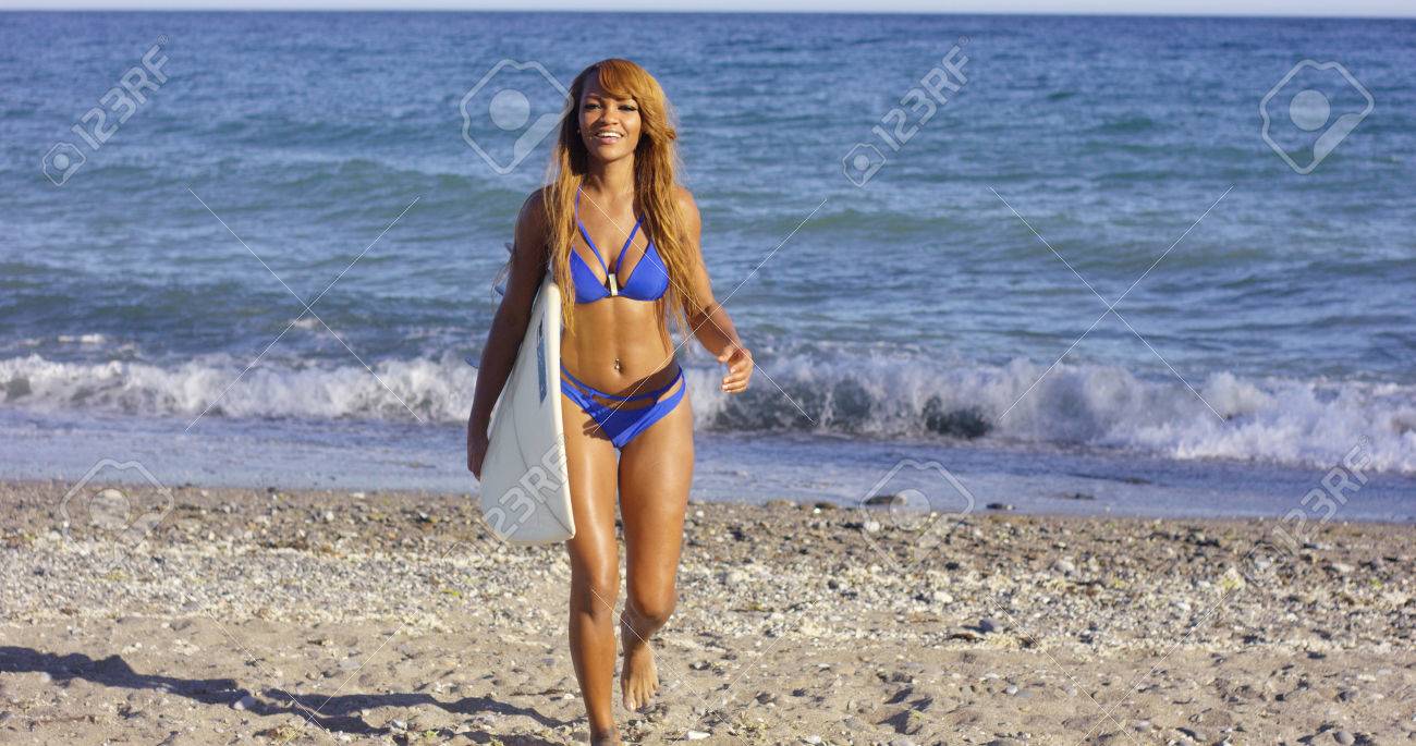 Sexy Femme Bronzée Marche Vers La Caméra Sur La Plage Avec Sa Planche De  Surf Sous Le Bras Et Un Sourire Heureux Sous Le Soleil D'été Banque  D'Images et Photos Libres De