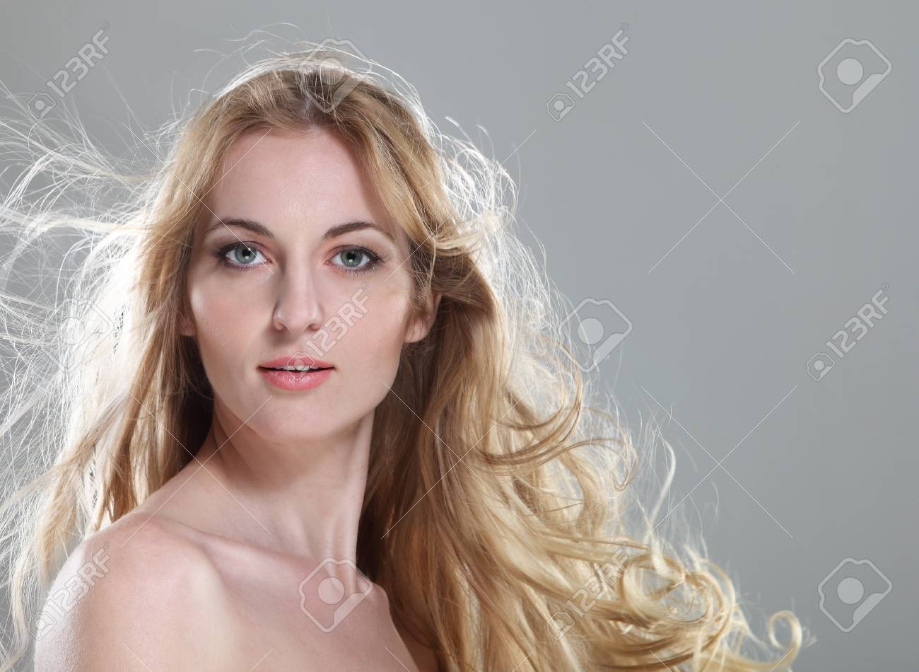 灰色の背景上の髪をなびくブロンドの若い女性 の写真素材 画像素材 Image