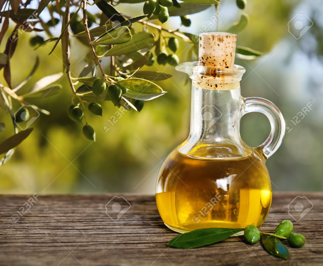 Olive oil and olive branch on the wooden table over nature background - 18363507 Olive oil and olive branch on the wooden table over nature background - 18363507
