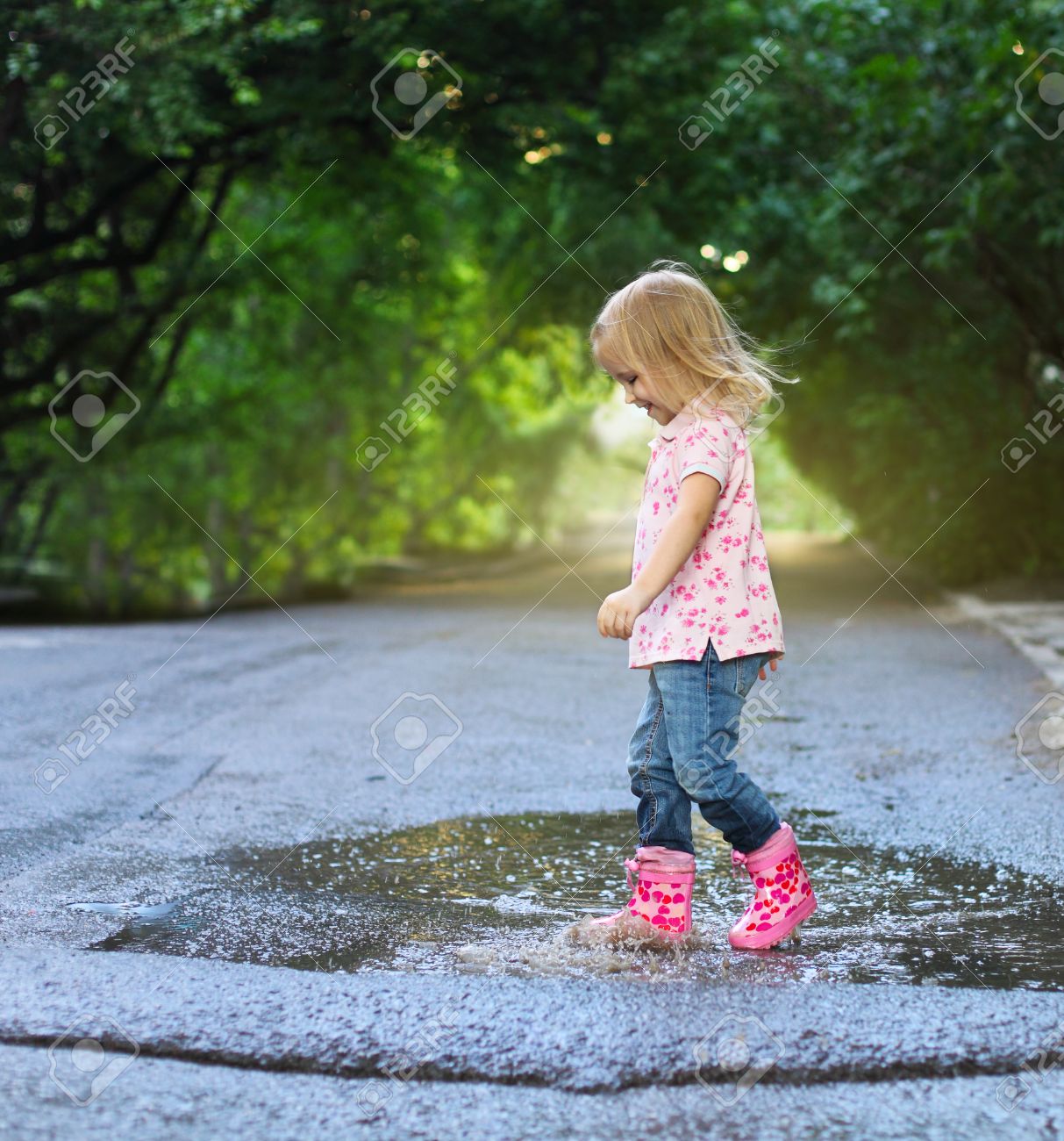 雨を着てかわいい女の子ブーツ水たまりにジャンプ の写真素材 画像素材 Image