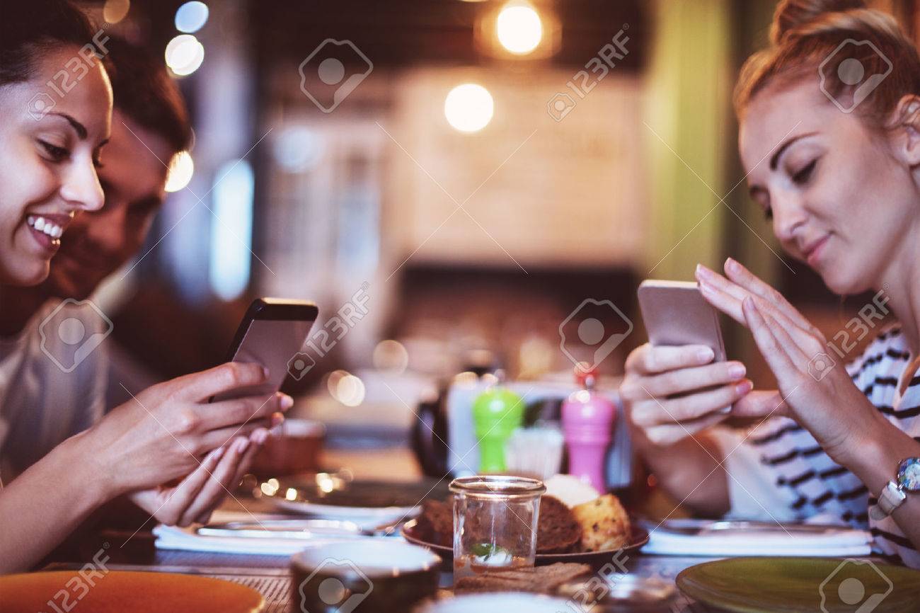 Happy friends take a food picture for instagram in cafe - 43958045 Happy friends take a food picture for instagram in cafe - 43958045
