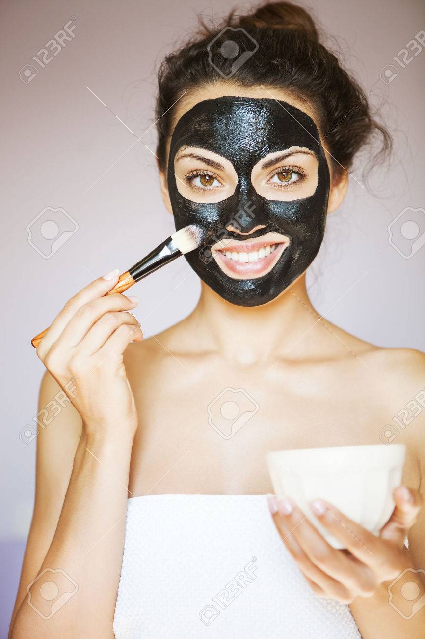 Young beautiful woman applying a mask for the face of the therapeutic black mud. Spa treatment - 46965046 Young beautiful woman applying a mask for the face of the therapeutic black mud. Spa treatment - 46965046