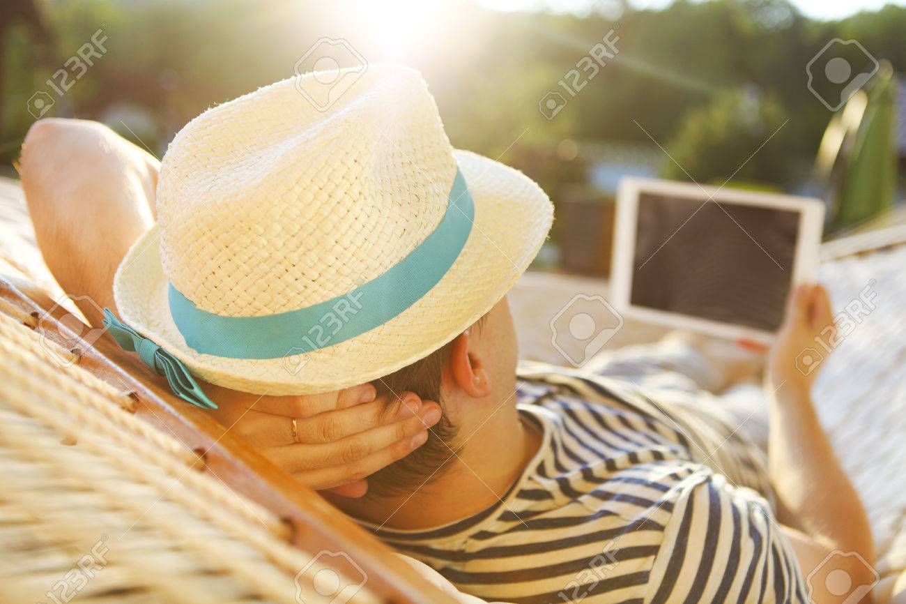 Lazy time. Man in hat in a hammock with tablet computer on a summer day - 51871950 Lazy time. Man in hat in a hammock with tablet computer on a summer day - 51871950