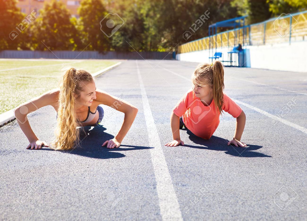 Mother and little daughter are doing exercise in the stadium. Family doing fitness at the stadium. Healthy family concept - 52314765 Mother and little daughter are doing exercise in the stadium. Family doing fitness at the stadium. Healthy family concept - 52314765