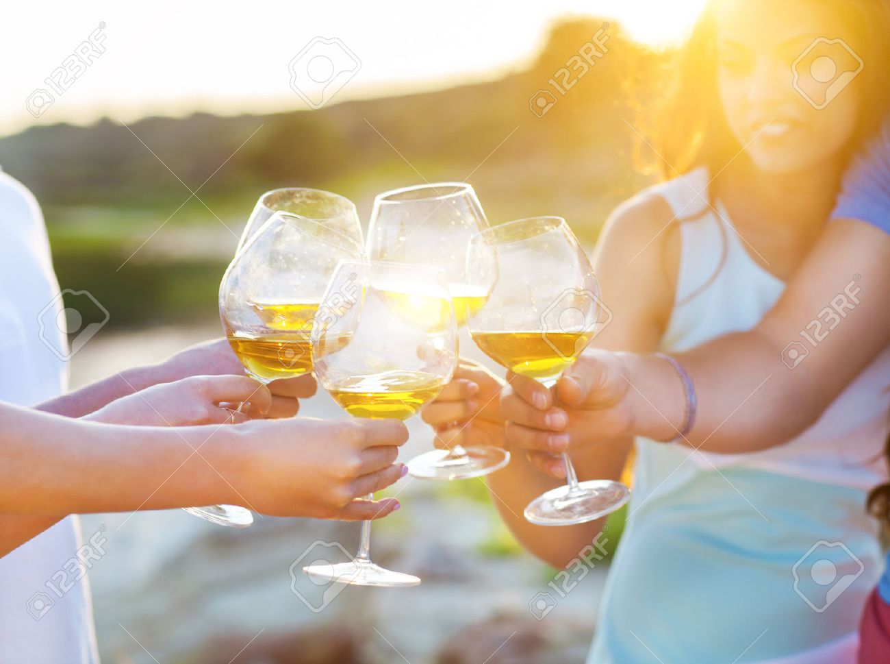 Celebration. People holding glasses of white wine making a toast. Sunset summer party - 52674474 Celebration. People holding glasses of white wine making a toast. Sunset summer party - 52674474