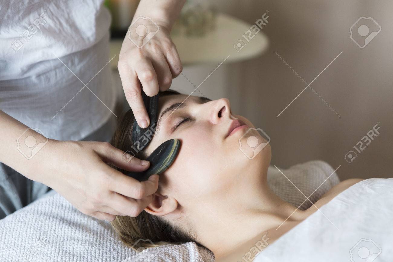 Young woman have face guasha treatment at asian beauty clinic - 84917160 Young woman have face guasha treatment at asian beauty clinic - 84917160