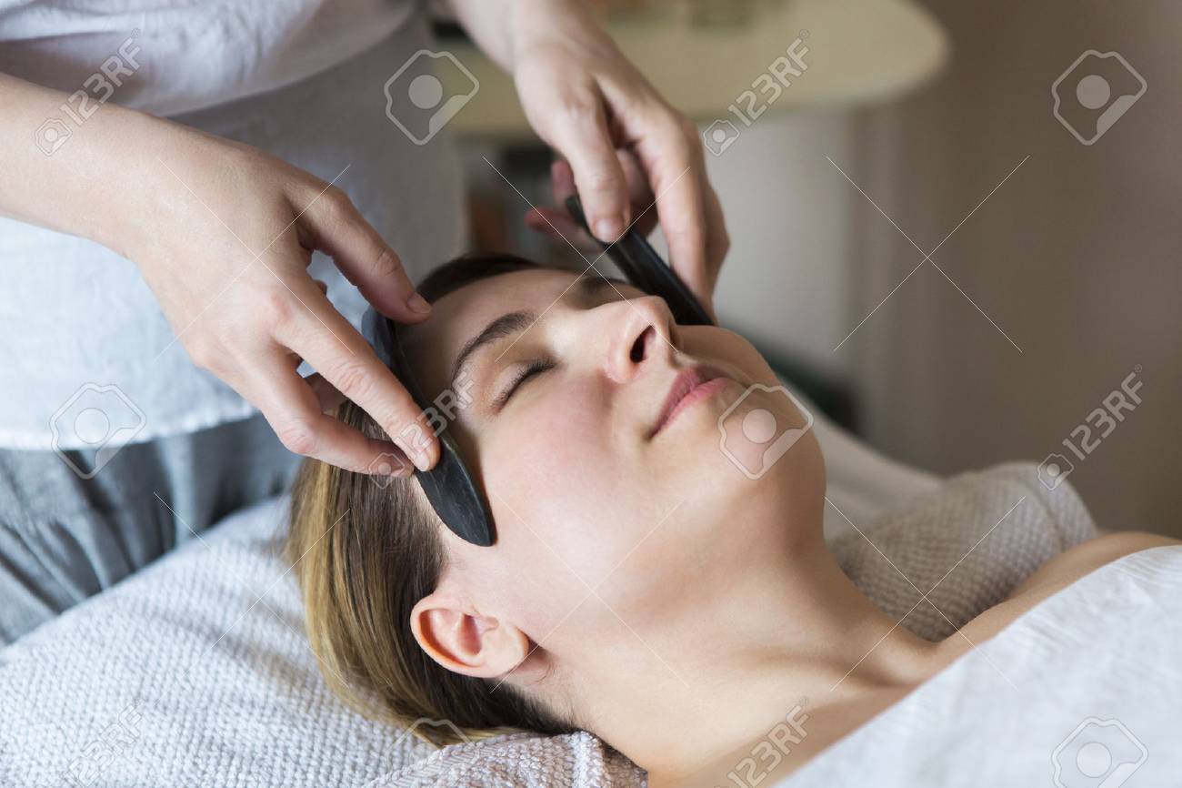 Young woman have face guasha treatment at asian beauty clinic - 85544222 Young woman have face guasha treatment at asian beauty clinic - 85544222
