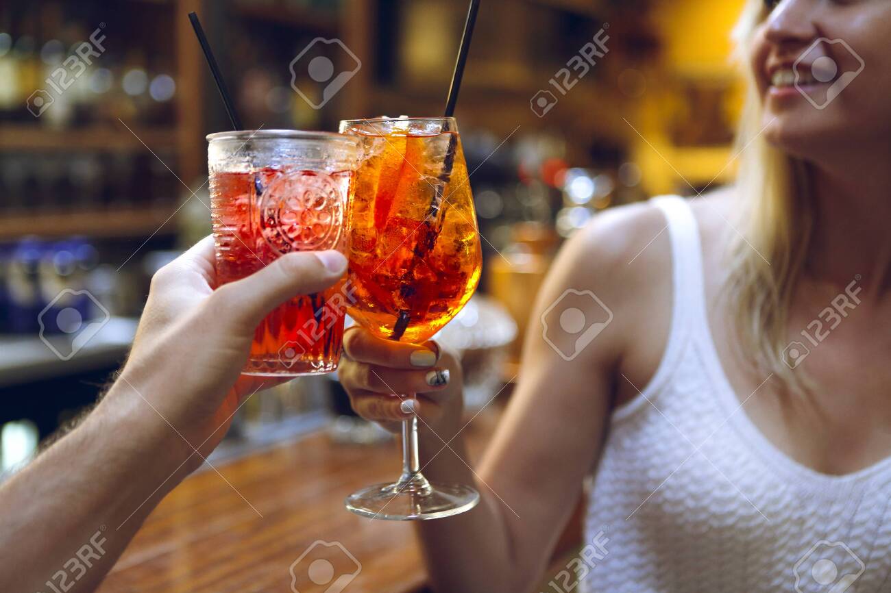 Woman and man raising a glasses of coktails in the bar background - 133884964 Woman and man raising a glasses of coktails in the bar background - 133884964