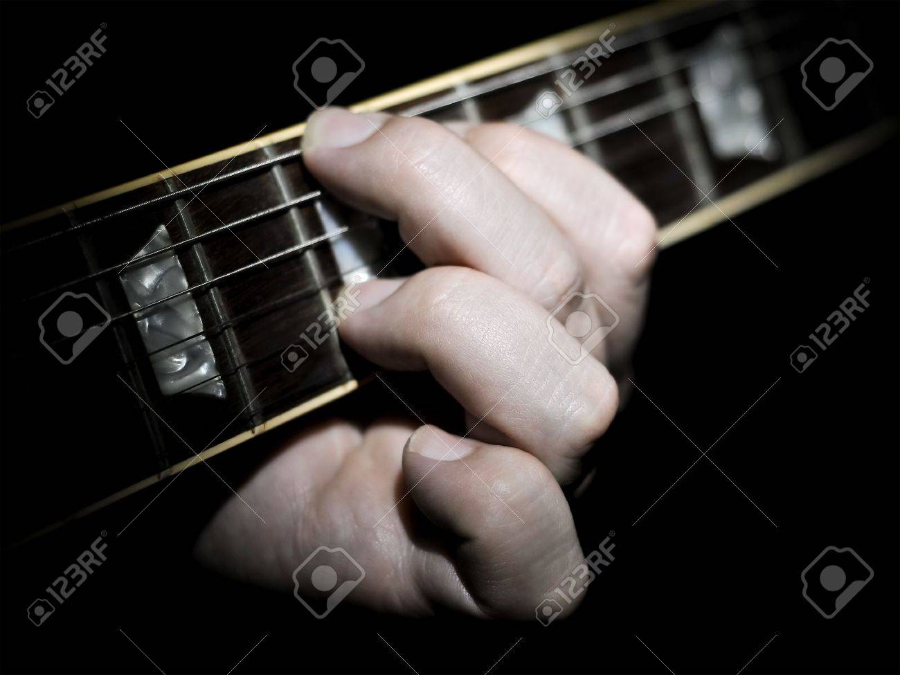 Guitar Player With Fingers On The Fretboard Fingering A Chord With A Black Background The Guitar Player With Fingers On The Fretboard Fingering A Chord With A Black Background The