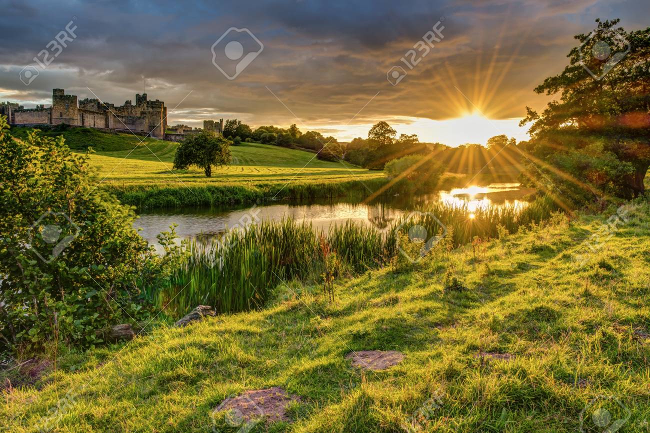 Sunbeams over River Aln at Alnwick, which runs through Northumberland from Alnham to Alnmouth. Seen here below Alnwick Town and Castle on the skyline, as the sun goes down - 84000358 Sunbeams over River Aln at Alnwick, which runs through Northumberland from Alnham to Alnmouth. Seen here below Alnwick Town and Castle on the skyline, as the sun goes down - 84000358