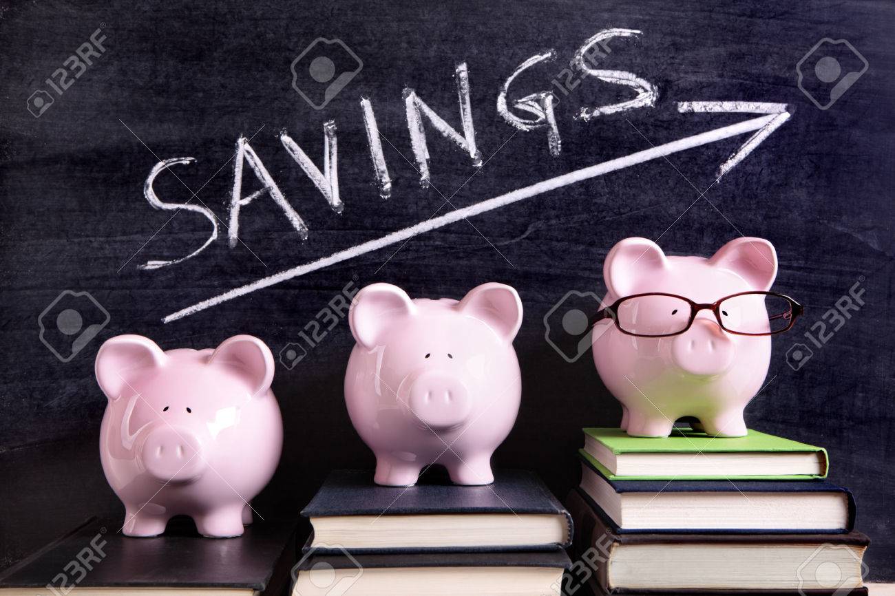 3 ピンクの貯金箱シンプルな貯蓄メッセージで黒板の横にある本の上に立っています シャープの貯金箱に焦点を当てる の写真素材 画像素材 Image