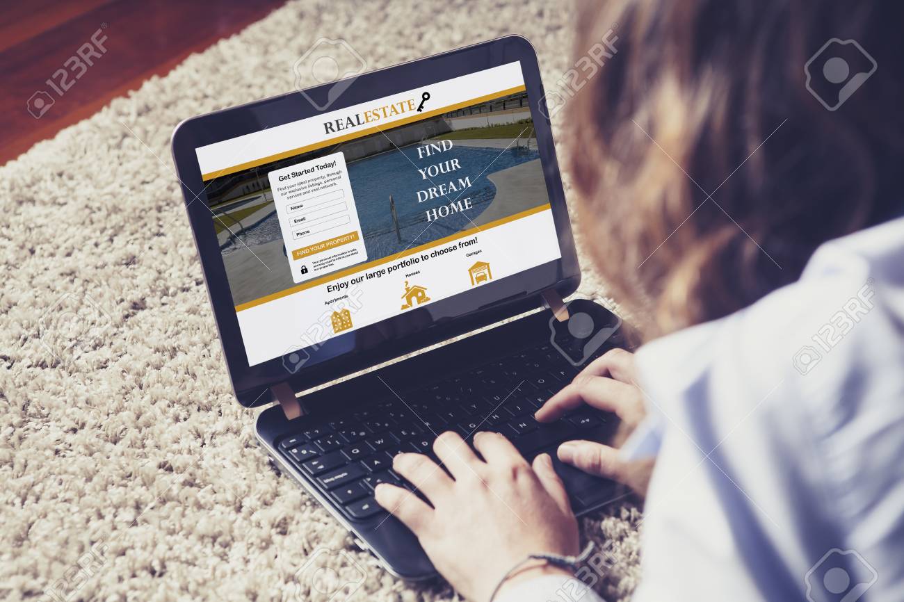 家で寝ながらノート パソコンでの不動産のウェブサイトの家を探している女性 の写真素材 画像素材 Image