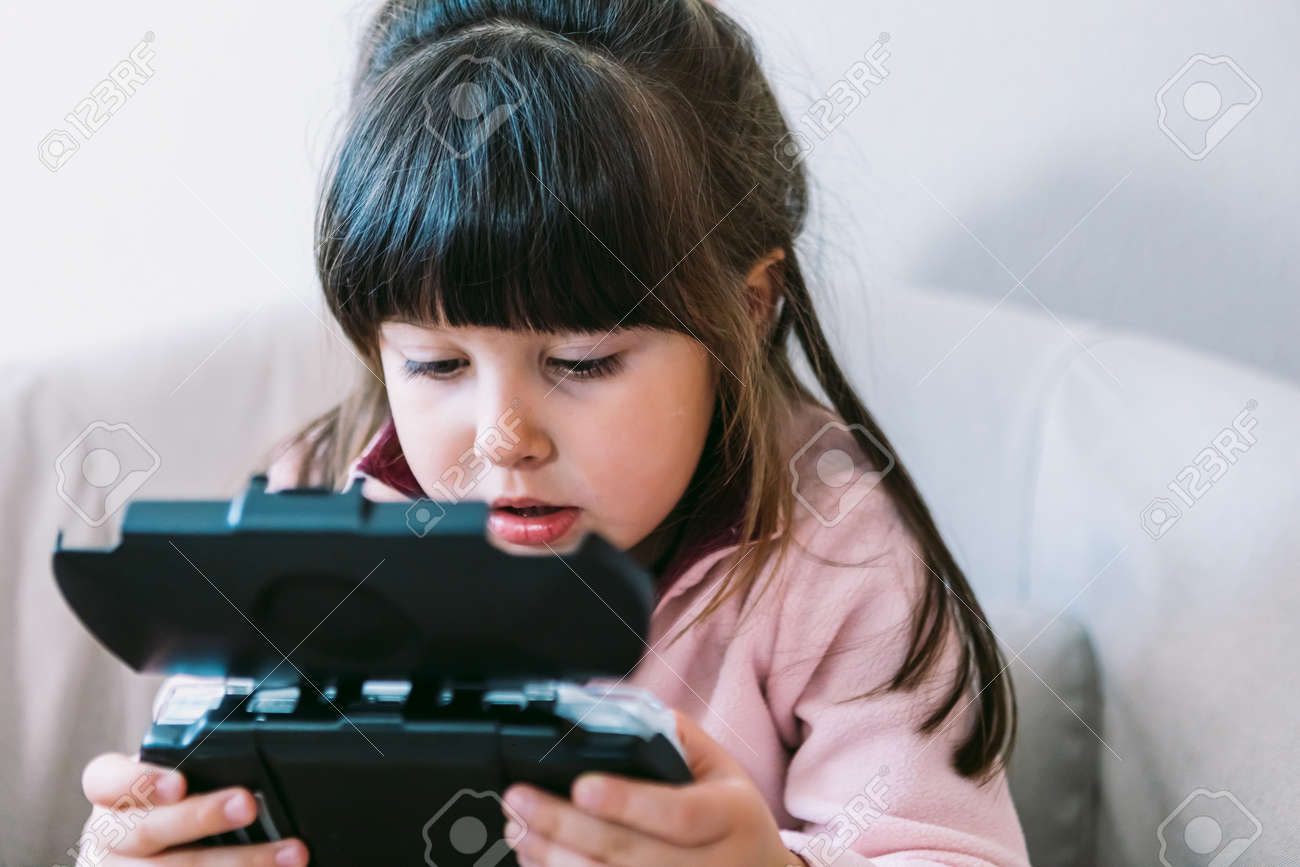 A menina com portátil joga o conceito dos jogos do vício do jogo