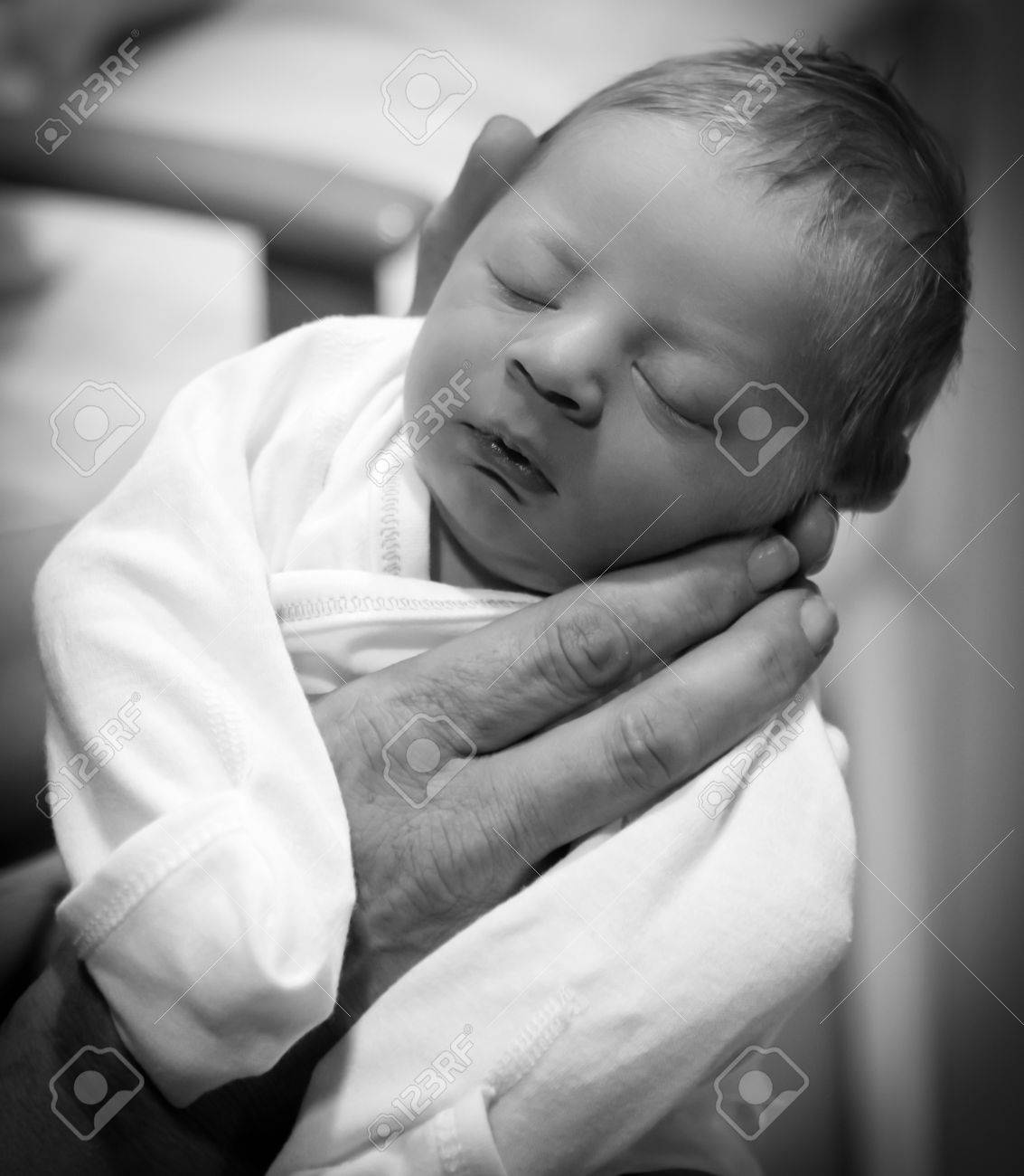 人間の手の寝ている生まれたばかりの赤ちゃんを保持している黒と白の写真 の写真素材 画像素材 Image