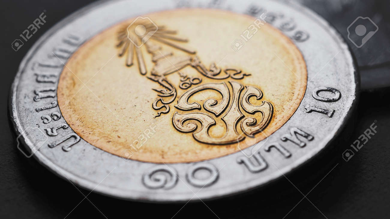 翻訳:10バーツタイ。10バーツのタイ硬貨は濃い黒の表面にあります 